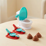 Tabletop game on a light wood table with a turquoise-lidded white toilet, two red-based launchers, and three brown toy poops.