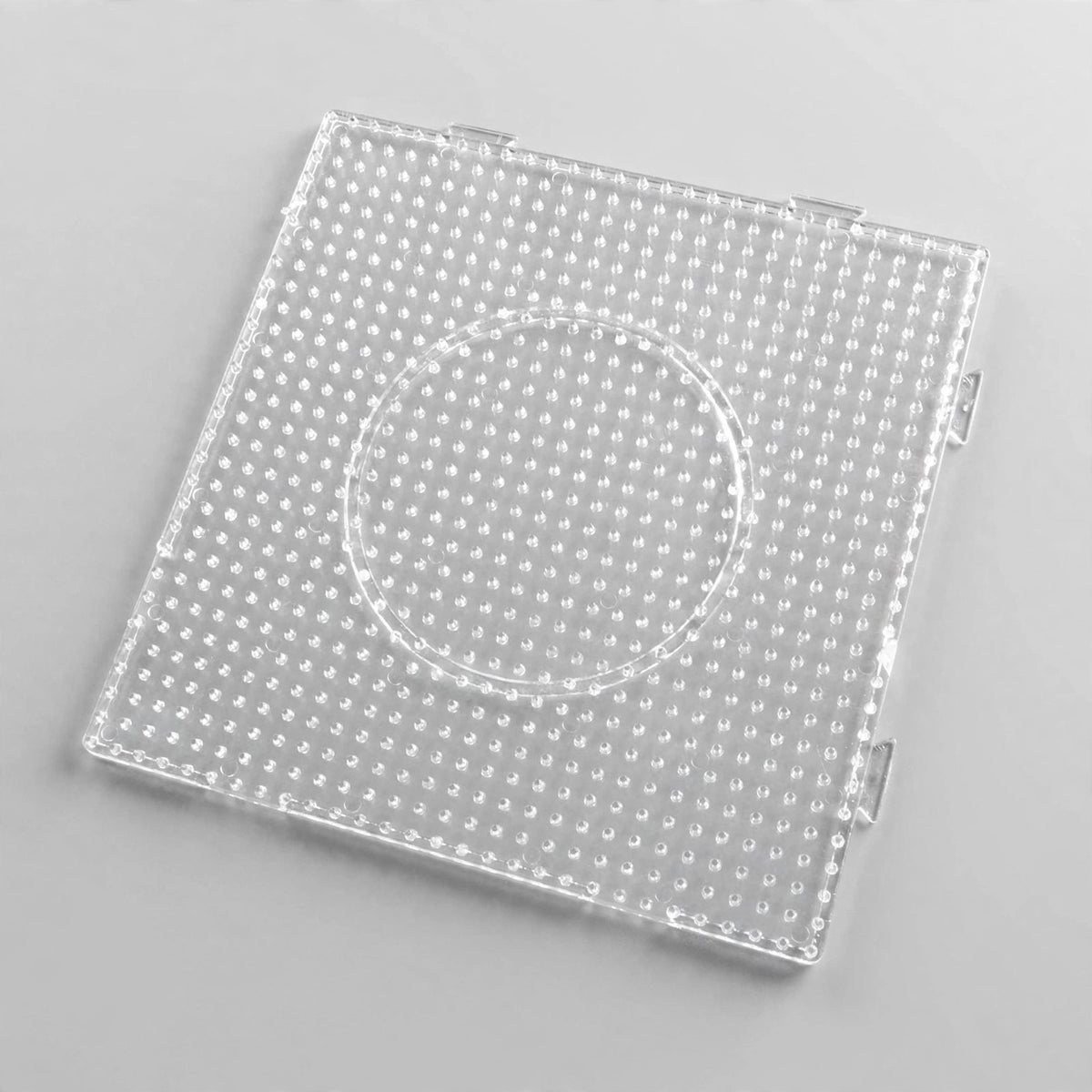 Clear square plastic pegboard with evenly spaced pegs, edge connectors, and a circular central outline on a light grey background.