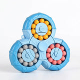 Blue plastic fidget puzzle with three rounded lobes and yellow, gray, and pink beads stands against a white background.