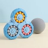 A blue plastic fidget puzzle with yellow, pink and grey beads stands beside a grey sphere against a pale blue background.