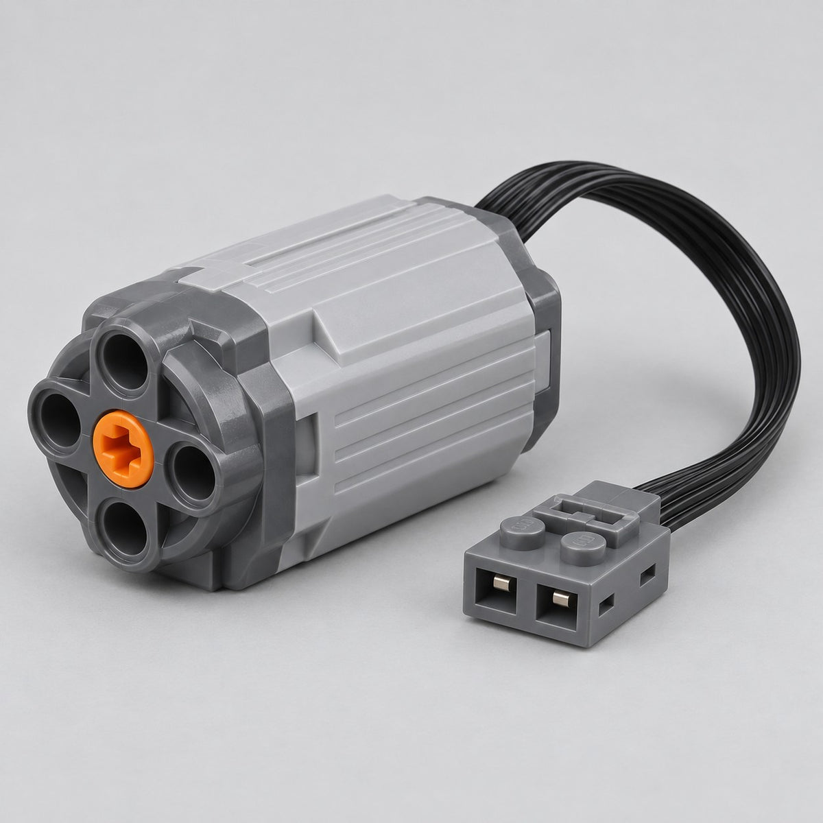 M Motor variant with its gray housing, orange shaft connector, cable and plug on a studio backdrop.