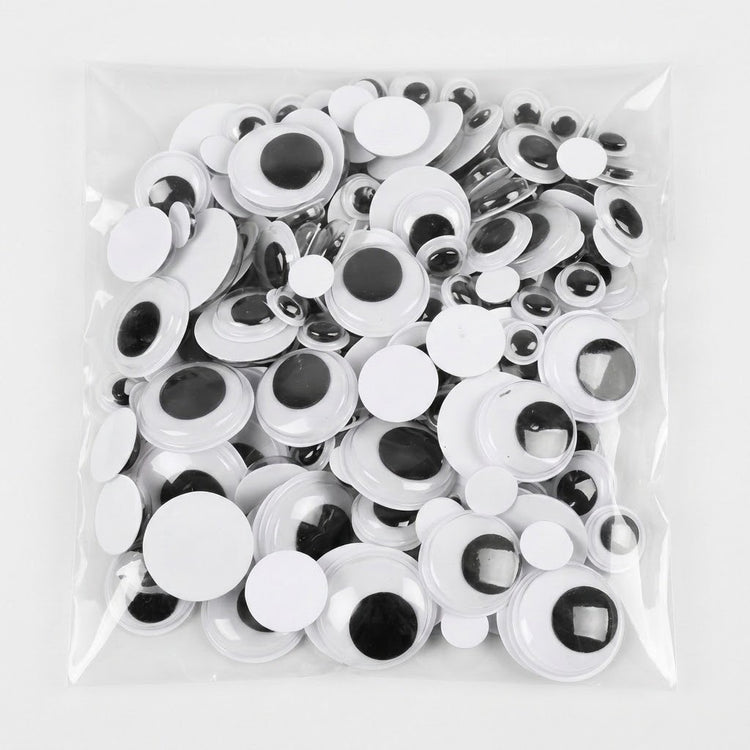 A clear plastic bag filled with many white googly eyes with black centers, photographed on a plain white background.