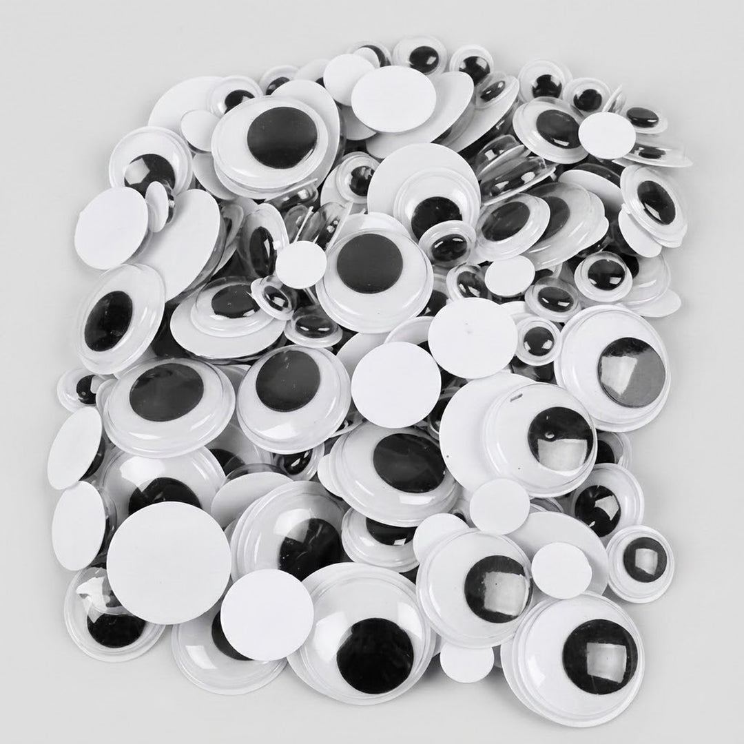 A pile of white plastic novelty googly eyes with black plastic pupils, photographed on a light gray background.