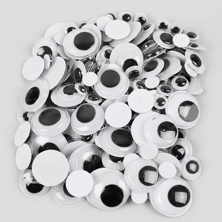 A pile of white plastic novelty googly eyes with black plastic pupils, photographed on a light gray background.