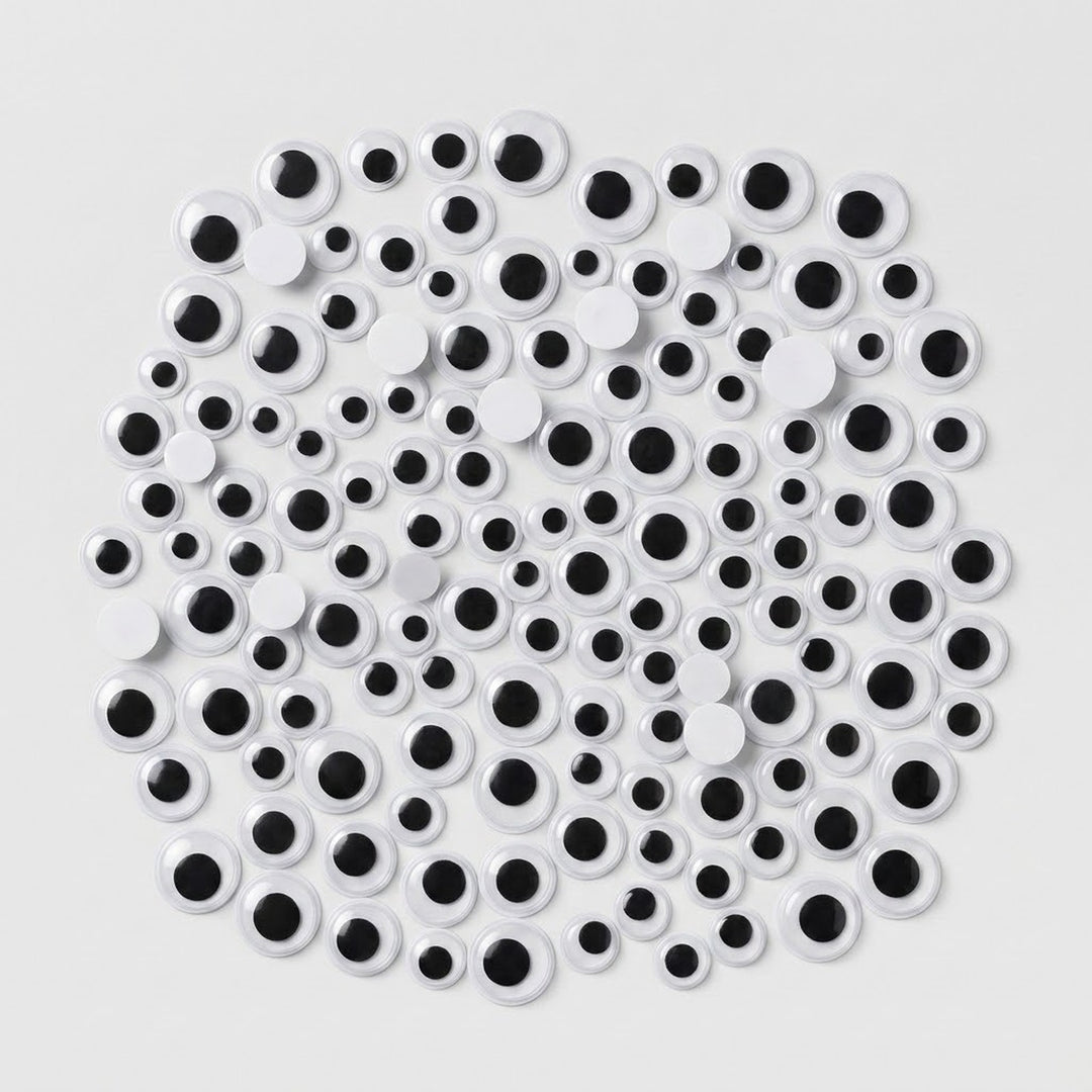 A pile of novelty plastic googly eyes in various sizes, featuring white circular bodies with black centers, arranged on a light gray background.