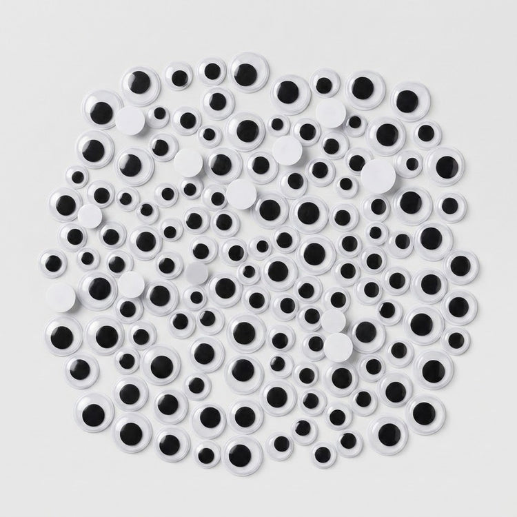 A pile of novelty plastic googly eyes in various sizes, featuring white circular bodies with black centers, arranged on a light gray background.