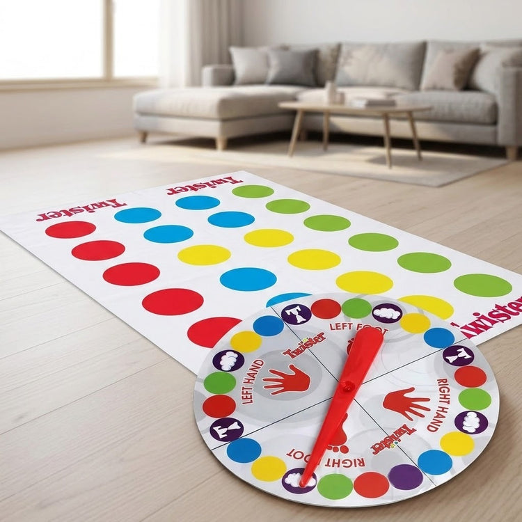 A party game mat with colorful circles and a round spinner with a red pointer rests on a wooden living room floor.