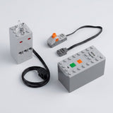 A gray model exhaust sprayer sits beside a battery case with green and orange controls, wired switch, and black cables on white.