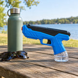 Blue manual water squirt gun sits beside a reusable bottle and sunglasses on a picnic table.