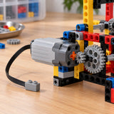Medium Power Functions motor drives a colorful building-block gear mechanism on a workbench.