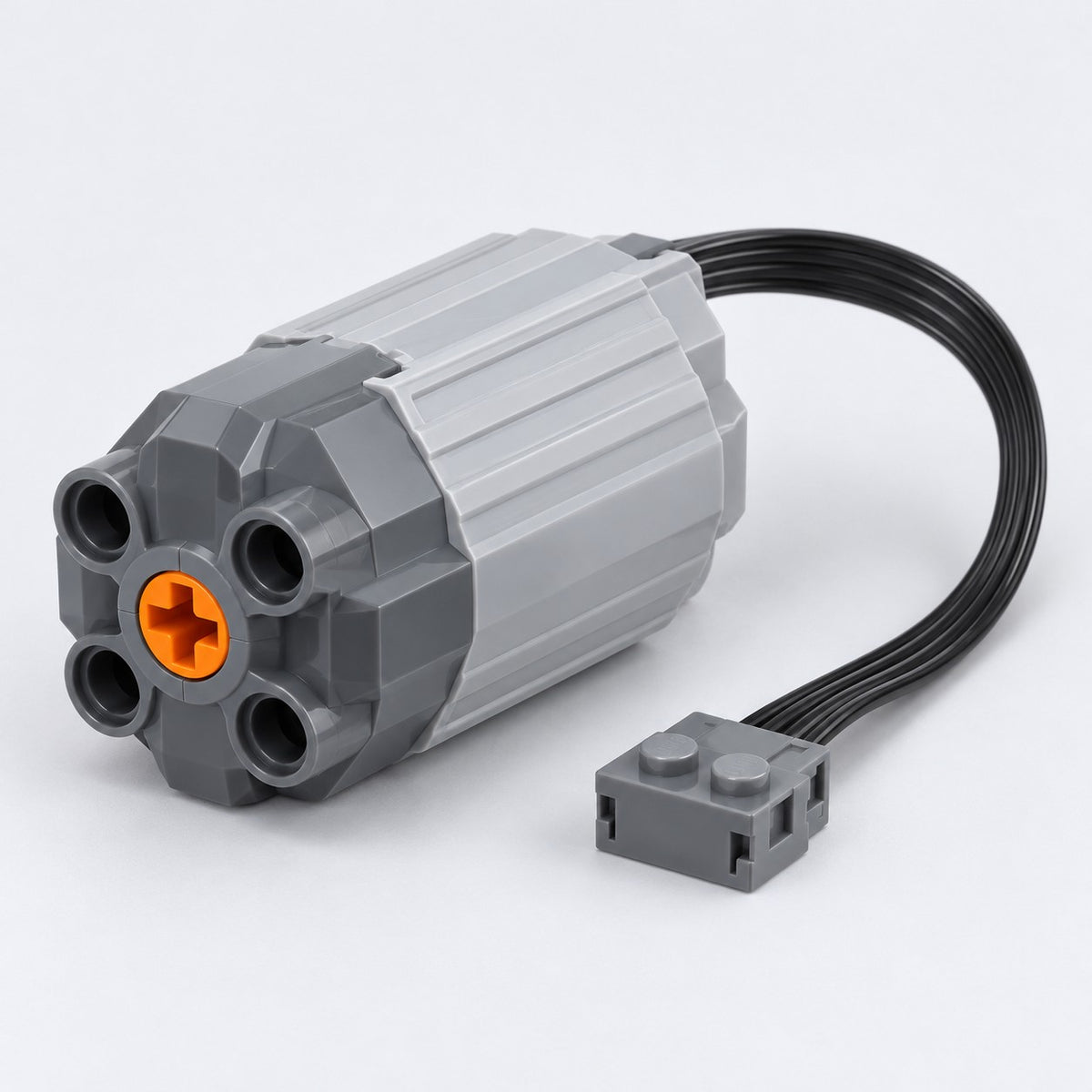 Medium building-block motor with attached cable and connector on a pale gray studio backdrop.
