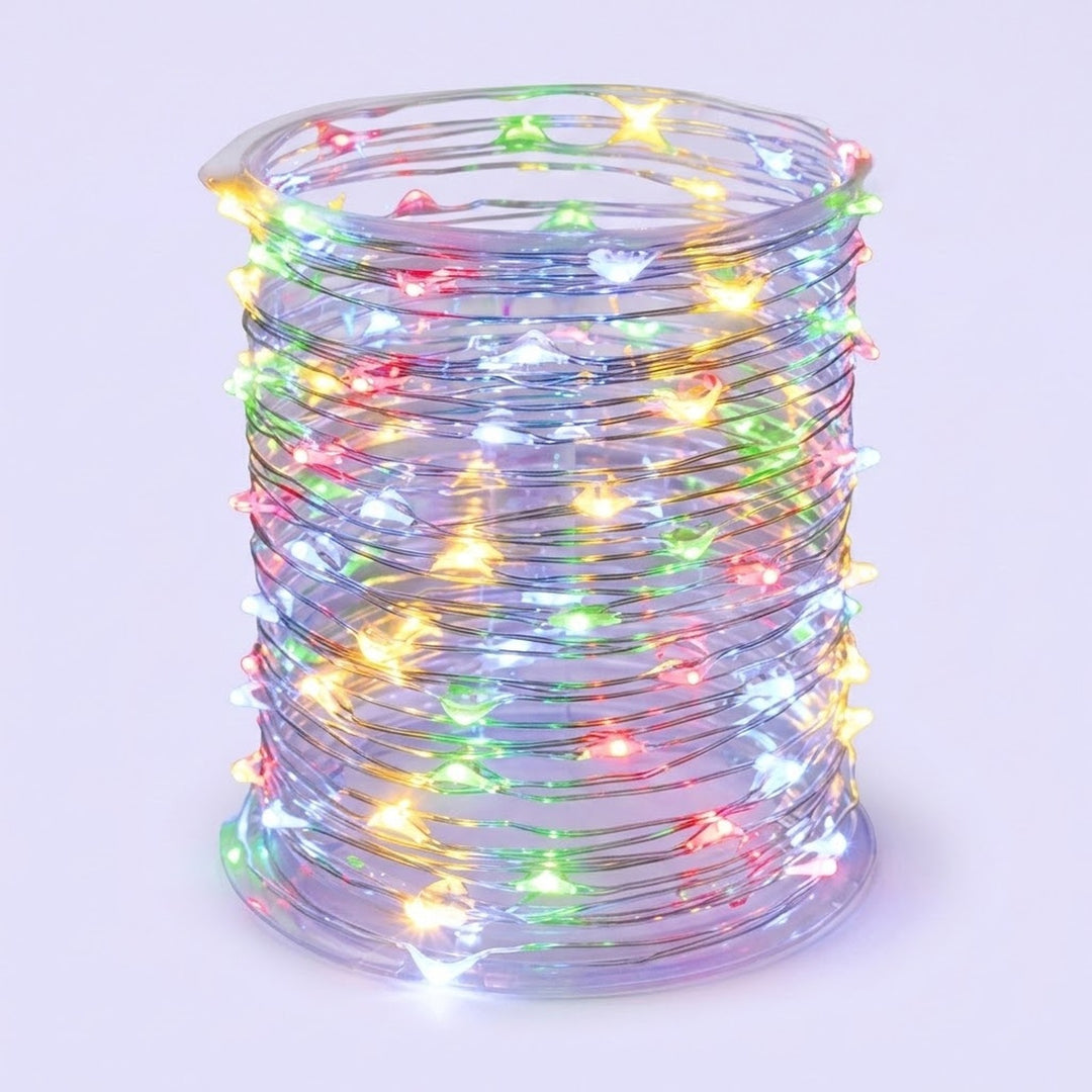 A coil of clear string fairy lights glowing with multicolor LED lights, including yellow, green, pink, blue, and white, set against a light lavender background.