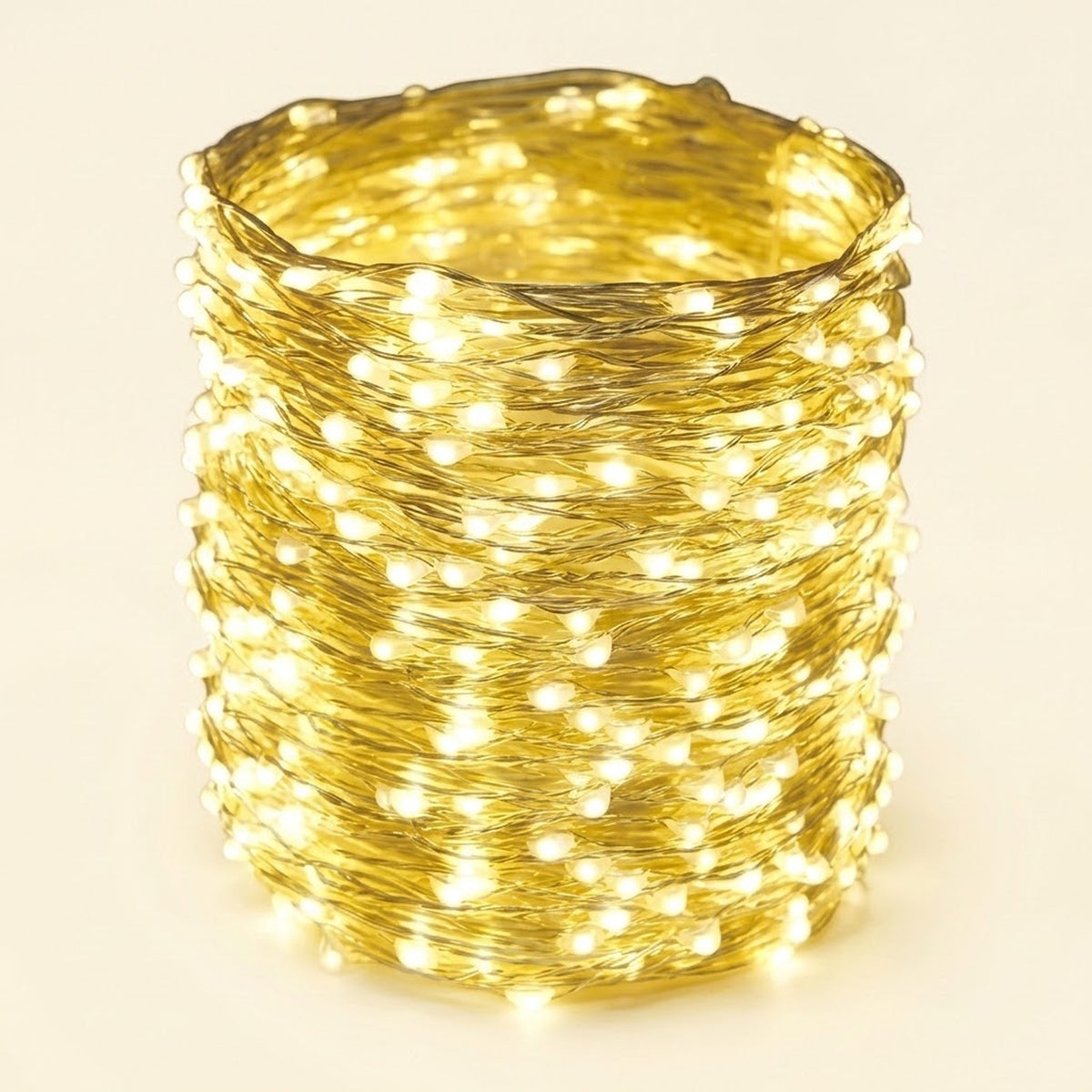 A coiled bundle of warm white LED fairy string lights wrapped tightly together, glowing brightly against a plain light beige background.