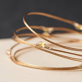 Close-up of the thin copper wire strand and small clear LED bulb of a fairy string light on a light surface.