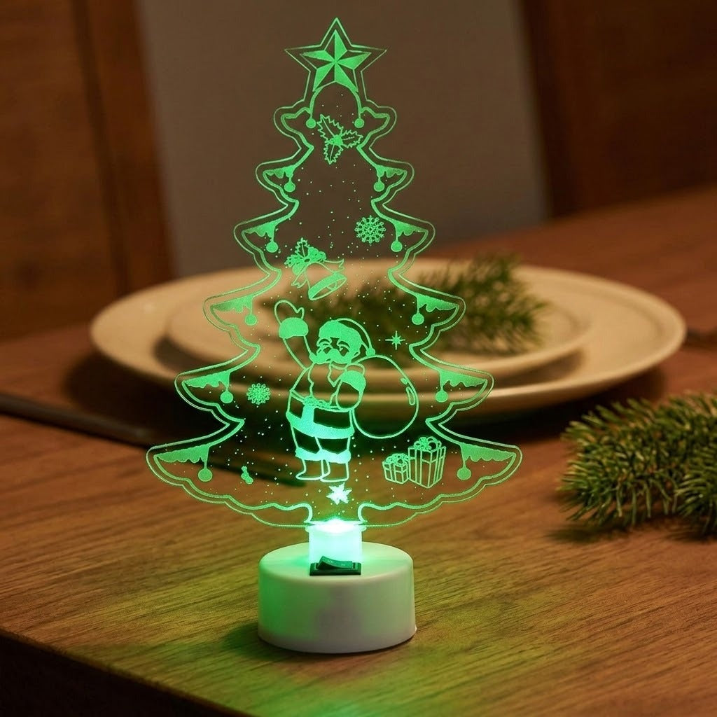 A 3D optical illusion LED night light shaped like a Christmas tree with Santa Claus and a gift, glowing green on a wooden table with plates and pine branches in the background.