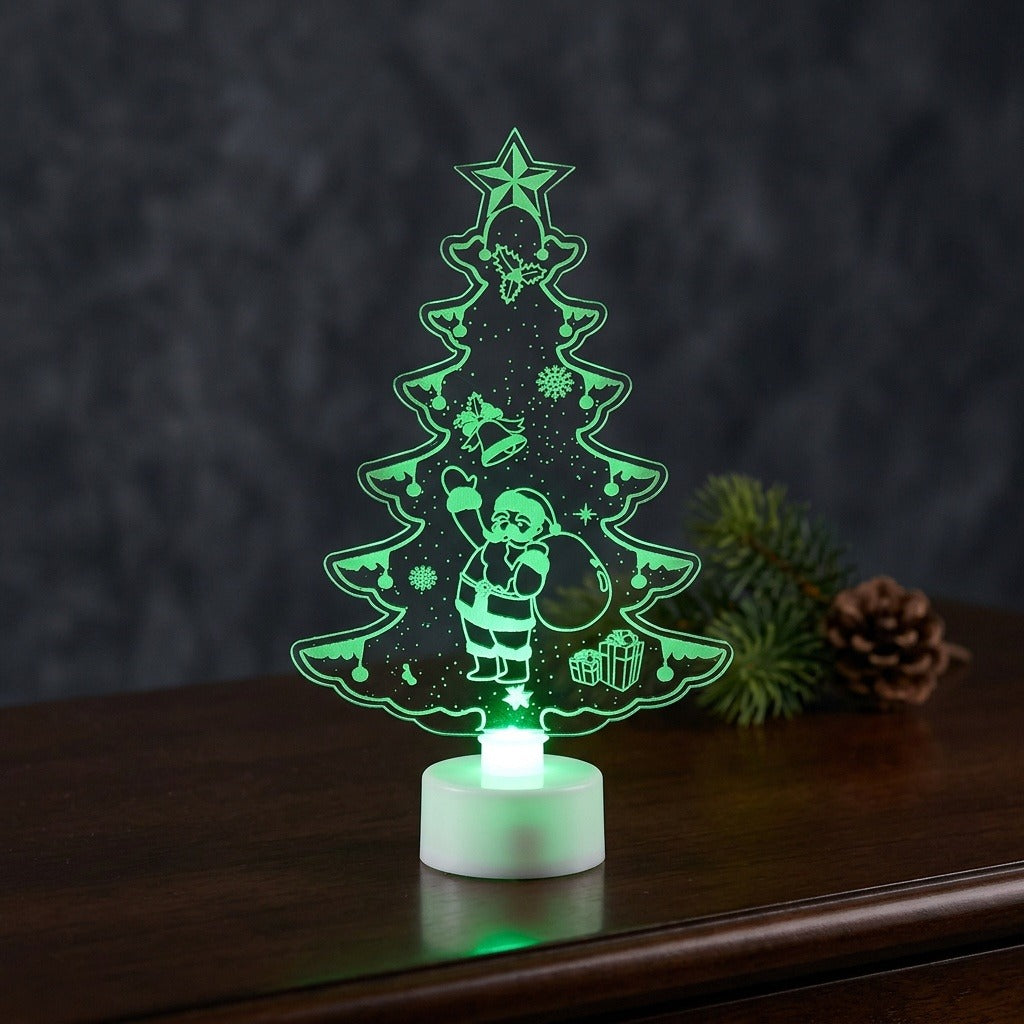 A Christmas tree shaped acrylic night light glowing green on a white base, standing on a dark wooden table.