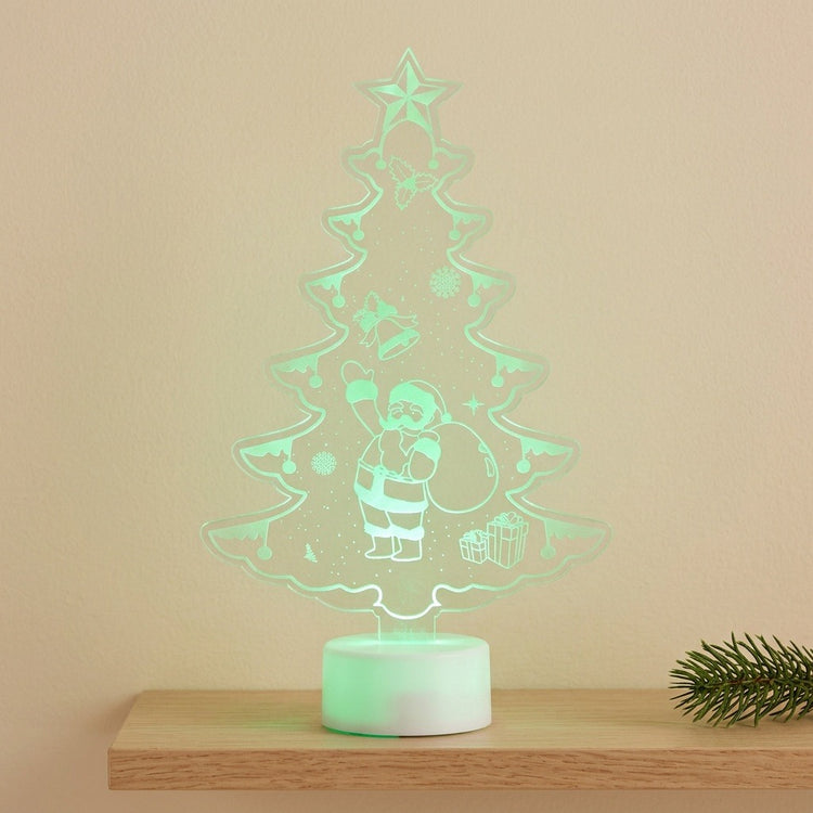 A glowing LED acrylic Christmas tree night light with a Santa Claus design, displayed on a wooden shelf against a beige wall.