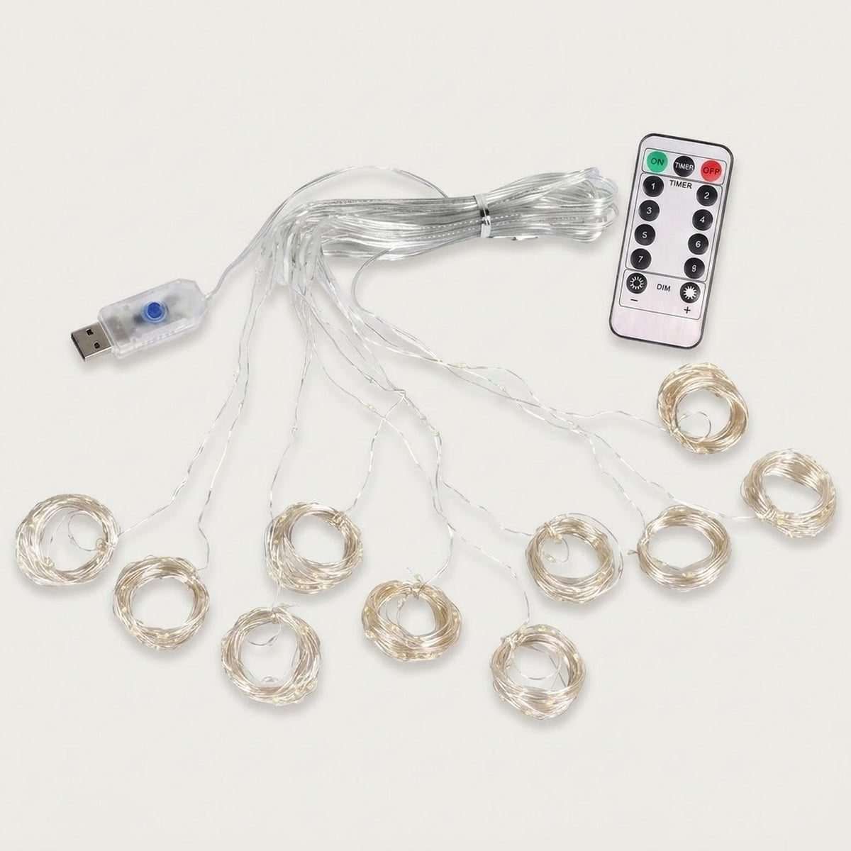 An unlit curtain light spreads clear strands into circular coils, with a USB connector and white remote on an off-white background.