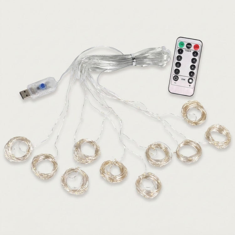An unlit curtain light spreads clear strands into circular coils, with a USB connector and white remote on an off-white background.