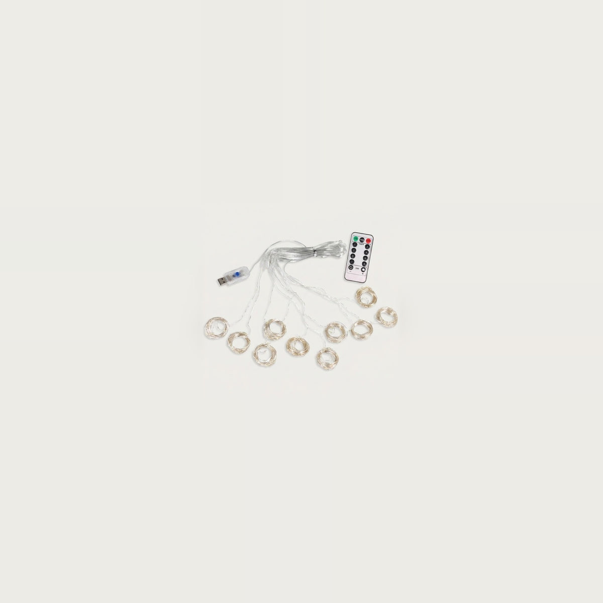 An unlit curtain light with clear wiring and small coiled strands sits beside a USB connector and white remote on an off-white background.
