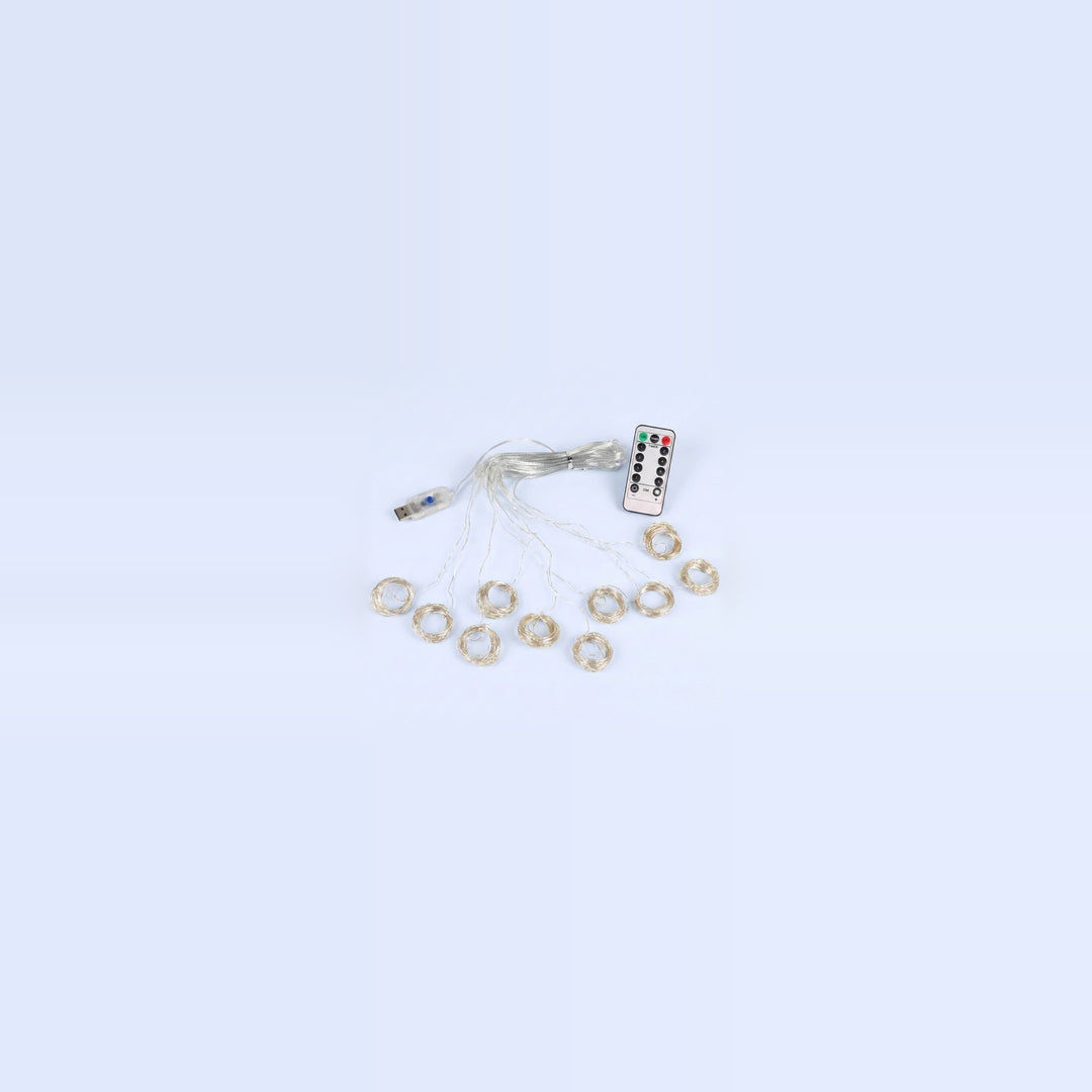 An unlit curtain light with clear wiring, small coiled strands, a USB connector and white remote rests on a pale blue background.