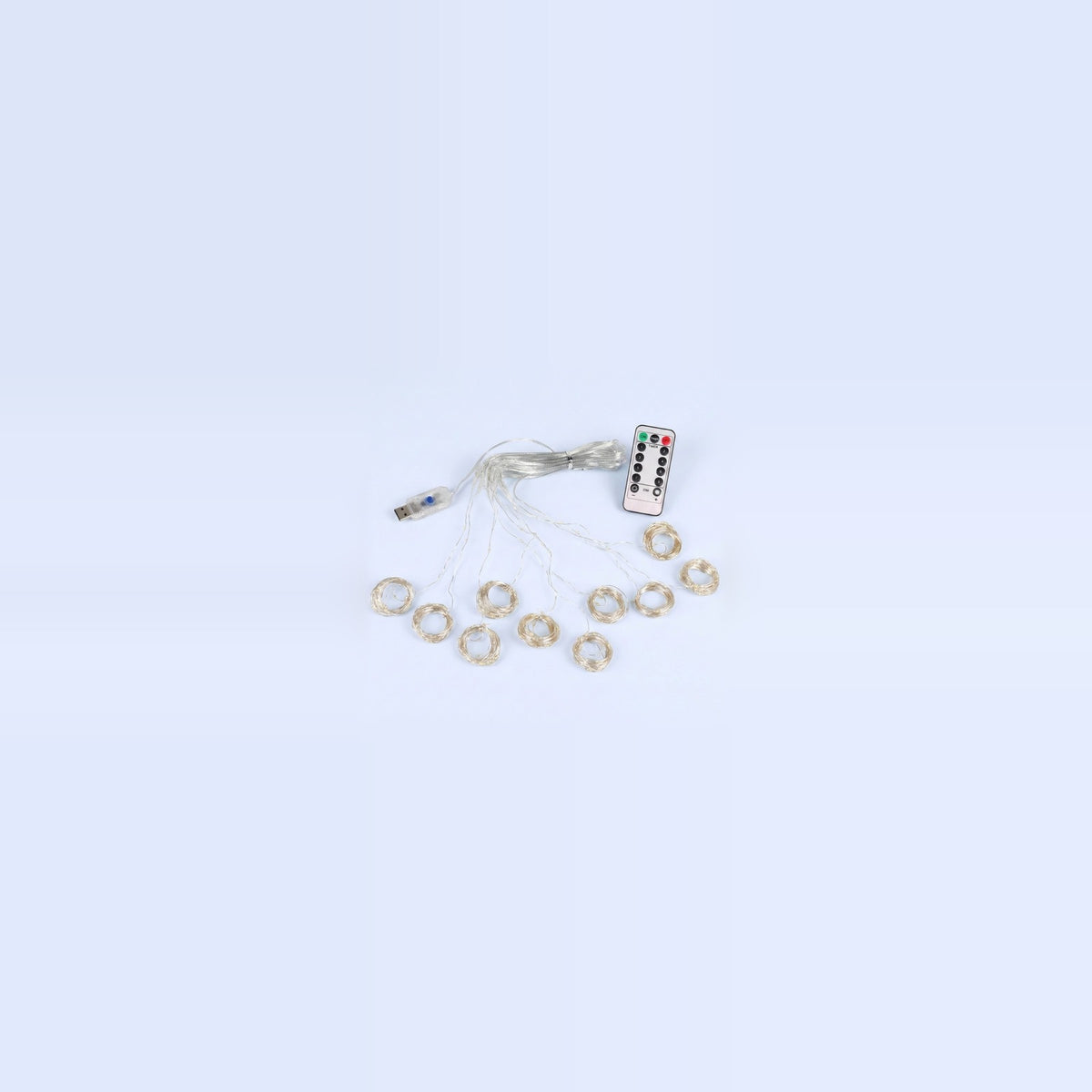An unlit curtain light with clear wiring, small coiled strands, a USB connector and white remote rests on a pale blue background.