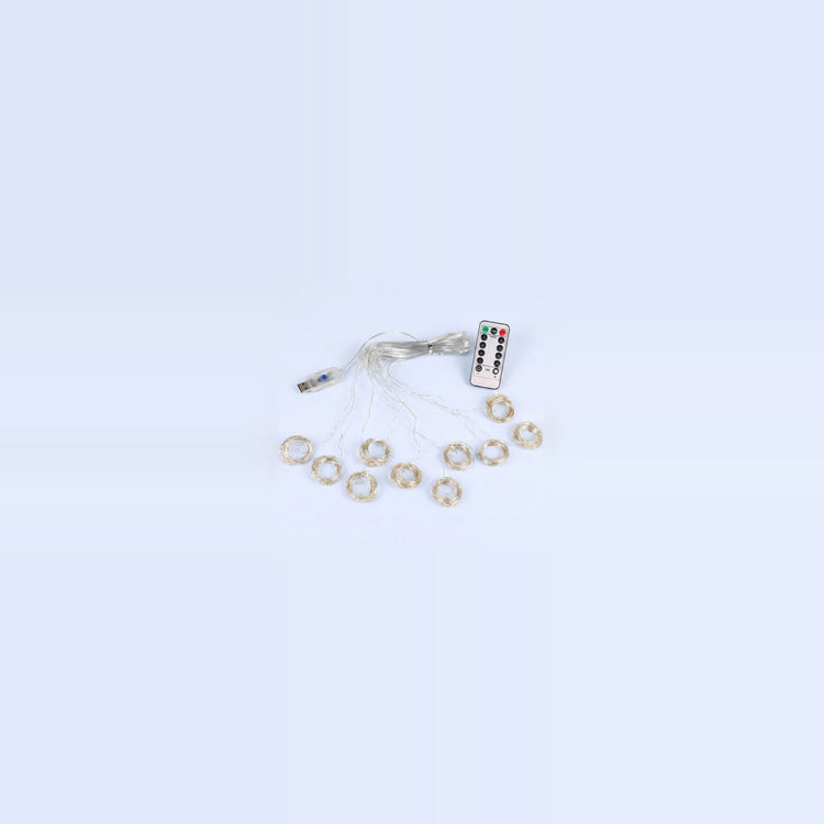 An unlit curtain light with clear wiring, small coiled strands, a USB connector and white remote rests on a pale blue background.