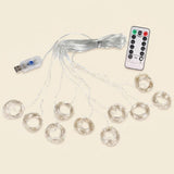 An LED curtain light’s coiled clear strands spread across a cream background beside its connected USB controller and white remote.