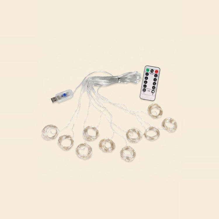 An LED curtain light with coiled clear strands, a connected USB controller and a white remote is arranged on a cream background.