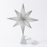 A silver glitter wire star tree topper with a spiral spring base, shown with its clear plastic power adapter on a white background.