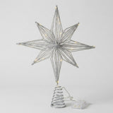 A silver wire star tree topper with warm white LED lights, mounted on a spiral spring base with a small clear plastic battery pack, shown against a light gray background.
