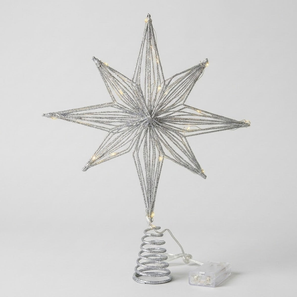 A silver wire star tree topper with warm white LED lights, mounted on a spiral spring base with a small clear plastic battery pack, shown against a light gray background.