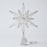 A silver wire star tree topper with warm white string lights, mounted on a spiral tree-shaped base with a clear power cord, shown against a light gray background.