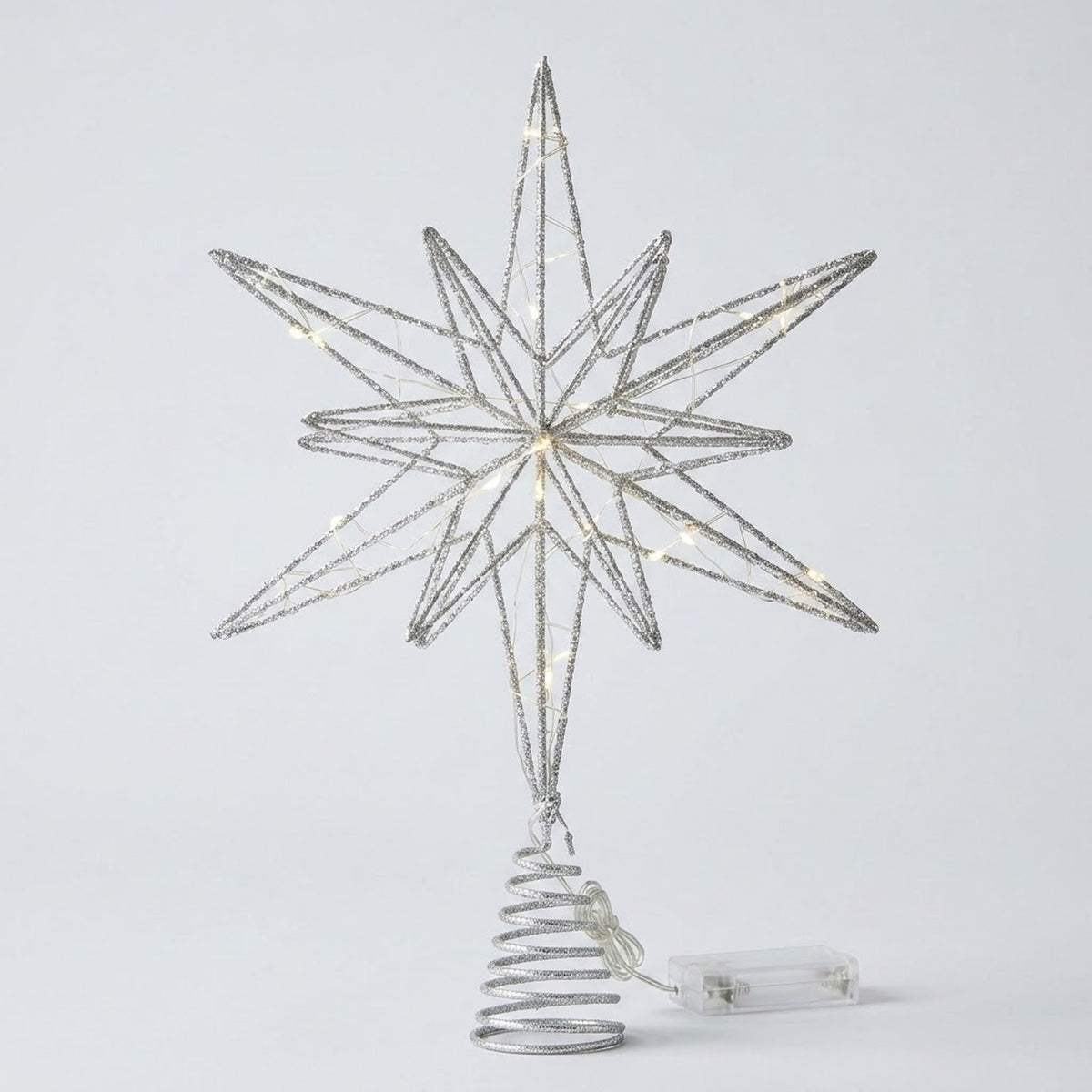 A silver wire star tree topper with warm white string lights, mounted on a spiral tree-shaped base with a clear power cord, shown against a light gray background.