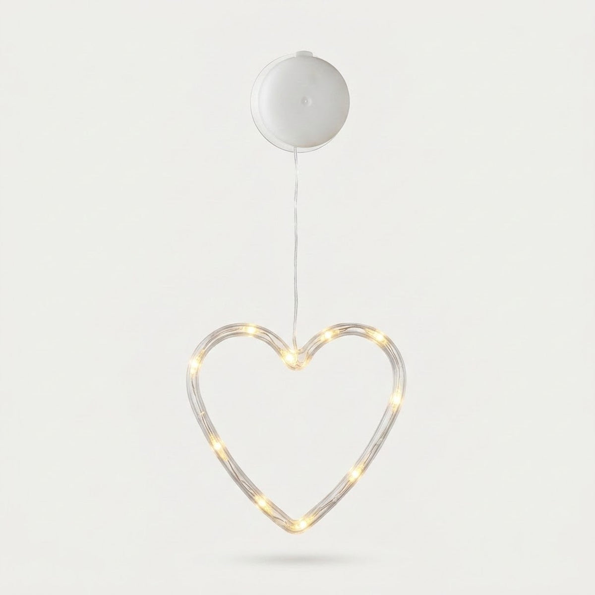Clear heart-shaped window light glows warm white beneath a round white battery box against a pale background.