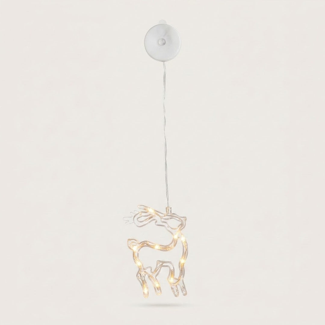 A clear reindeer-shaped window light with warm LEDs hangs beneath a round white housing against an off-white background.