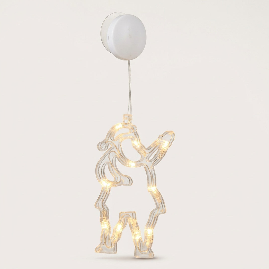 Clear Santa Claus-shaped window light glows warm white beneath a round white battery box and suction cup against a pale background.