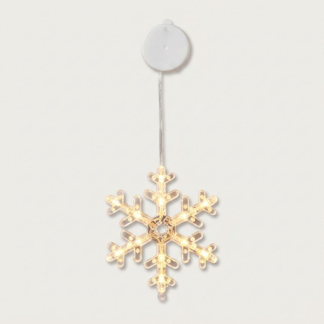 A clear snowflake-shaped window light glows with warm LEDs beneath a round white housing against an off-white background.