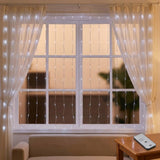 Cool white LED curtain lights cover a white-framed window above a beige sofa, with a remote resting face down on a wooden table.