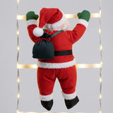 Christmas string lights surround a close rear view of the Santa ornament, showing its red suit, green mittens, and dark sack.