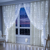 White curtain panels with hanging string fairy lights illuminated in front of a window at dusk, shown in a styled room with a chair and side table.