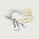 Wireless LED fairy string lights with a coiled bundle of white wires, a set of gold-toned light rings, a USB charging cable, and a black remote control on a light gray background.