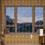 Warm white curtain string lights hanging in vertical strands across a windowed wall, with a remote control and power adapter shown in a cozy room setting.