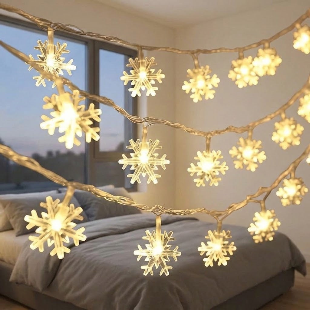 Warm-white snowflake curtain lights on clear wire drape across a bedroom with gray bedding and a window.