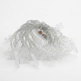 Unlit snowflake curtain lights with clear wire lie coiled on a white background.