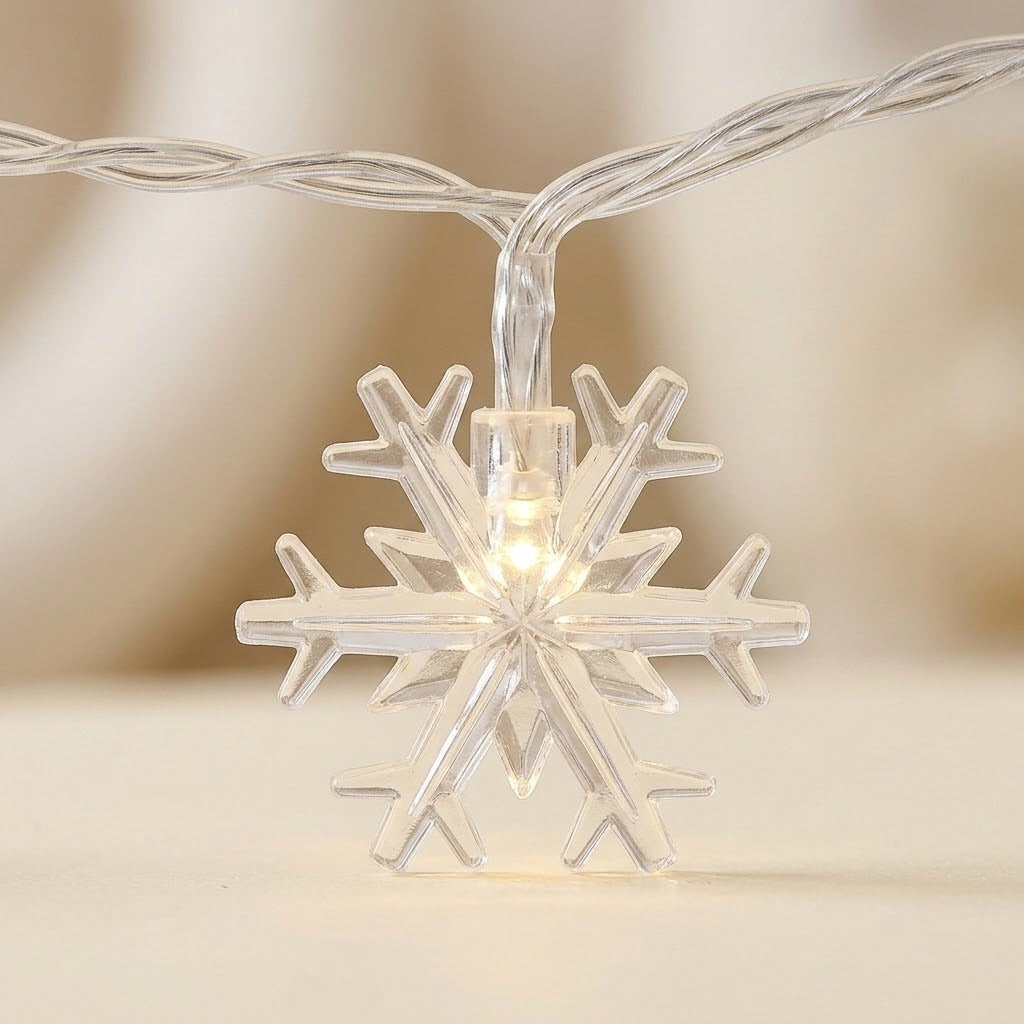 Snowflake curtain lights feature a clear snowflake glowing warm white on twisted clear wire against a blurred cream background.