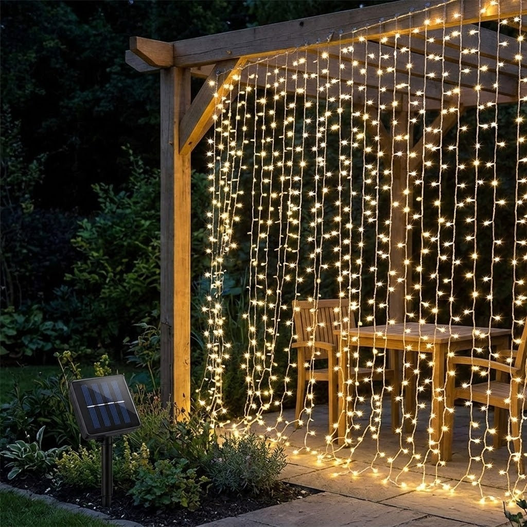 Warm white LED curtain string lights hanging from a wooden pergola in a backyard patio setting, with a small solar panel stake visible on the left.