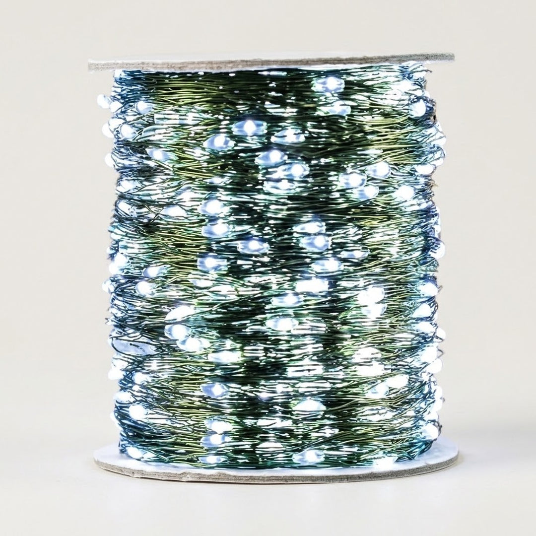 A cool white LED string light with green cable glows around a spool against a plain light beige background.
