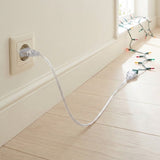A transparent extension cord connects a wall outlet to multicolored string lights across a pale wood floor beside a window.