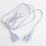 A clear plastic extension cord with a two-pin European plug on one end and a three-pin plug on the other, coiled on a white background.